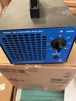 Front view of the blue ozone generator showing timer dial, ventilation panel, and reset light.