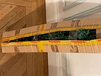 Photo of the boxed small artificial Christmas tree with visible green branches and some ornaments inside the box.