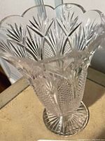 Top portion and rim of clear Waterford crystal vase showing intricate cut glass detailing and slight damage near top edge.