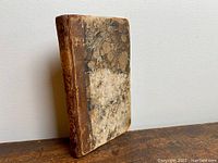 Front cover of French book showing worn marbled paper and dark leather spine with visible scuff marks and discoloration.