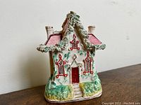Front and side view of the 19th century Staffordshire pottery cottage figurine showing hand-painted detailing and overall condition.
