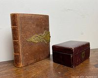 Both antique boxes side by side on a wooden surface against a plain wall, showing size comparison and visible details.