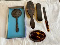 Photo showing full collection of the dresser set elements including sterling silver mirror and tortoiseshell grooming items.