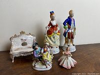 Overview of the porcelain figurines and decorative bench showing overall condition and style