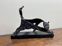Side profile view of stretching cat sculpture on rectangular base