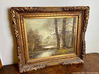 Framed oil painting showing the full artwork and decorative frame, highlighting the landscape scene.