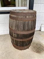 Full view of old wooden barrel showing its weathered wood and rusted metal bands.