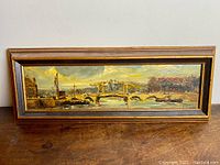 Full frontal view of the framed oil painting showing the entire harbor scene with boats, buildings, and bridge.