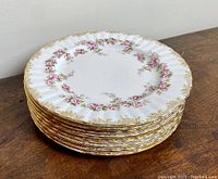 Stack of 8 vintage Royal Albert Dimity Rose dessert plates showing floral pattern and gold trim on a wooden surface.