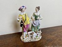 Front and side views showing shepherd man and woman standing on decorated base with lamb, detailed painted colors and missing staff tip.