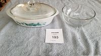Covered casserole dish with clear lid and green fruit pattern next to medium clear glass bowl