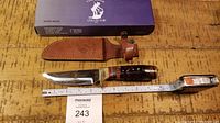 Full view of knife, sheath, ruler showing approx 10-inch length, and original box.