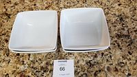 Four white square bowls stacked on granite countertop, showing shape and size.