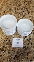 Five white ceramic bowls stacked and shown individually on countertop.