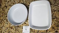 Two white ceramic bowls placed on granite countertop, rectangular pan and oval bowl shown side by side