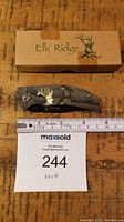 Elk Ridge folding pocket knife closed with box, next to ruler showing size about 3 inches closed, and overall length about 6 inches.
