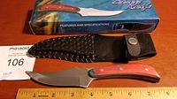 Hunting knife with wood handle, stainless steel blade, and black textured leather sheath.