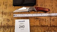 Photo showing unfolded pocket knife with stainless steel blade, wooden handle inlay and a ruler showing approximately 8 inches in length.
