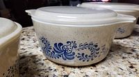 Close-up of 7.5 inch Pyrex bowl showing blue floral design and white lid on granite countertop.
