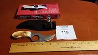 Short Skinner knife with polished antler or bone handle, finger hole, stainless steel curved blade, and ruler for scale showing 6 inch overall length, with black leather sheath and original box.