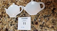 Two white ceramic tea bag holders placed on granite countertop next to MaxSold label showing lot number 11 and quantity 2.