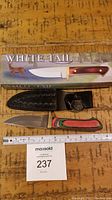 Knife packaged in original White Tail box alongside the knife with sheath and belt loop.
