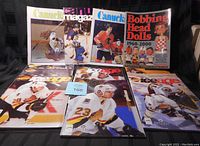 Full view of seven Canucks programs, Bobbing Head Dolls book, and two Ice Age hockey magazines laid out on black background