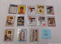 Overview photo of multiple hockey and baseball trading cards in hard cases showing front and back of cards with player images and team photos