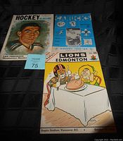 Photo of the three vintage sports programs laid out on a black surface, showing the 1958 Blueline Hockey program with Lou Fontinato portrait, 1963-64 Canucks coupon cutout with hockey logos and illustrations, and 1964 BC Lions football program with cartoon player cover.