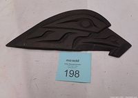 Front view of dark wood carved eagle head with stylistic, geometric Native design elements.