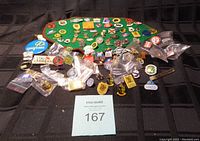 Overview of the large pin collection displayed on green fabric and sorted with some pins in plastic bags.