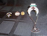 Four Masonic pins displayed on a black fabric background, showing their size, details, and condition.
