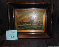 Frontal view of the old small oil painting showing ships on water with gold trim and dark wood frame.