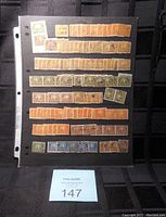 A single black stock sheet page filled with multiple rows of used Canadian stamps mostly orange, green and blue.