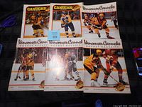 Six Vancouver Canucks hockey game programs from the 1980s laid out on a surface, showing covers featuring players and team colors.