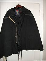 Full front view of the black heavy-duty jacket with open zipper revealing inside vest lining.