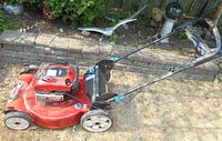 Side view of red Toro lawn mower showing overall condition and structure including handle and wheels.