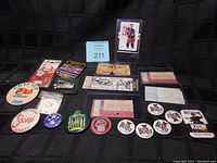 Wide group shot showing vintage concert tickets arranged with various music and radio station buttons and pines in front of a black background.