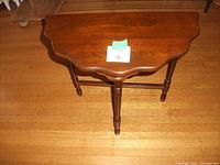 View of the walnut side table showing the D-shaped top, scalloped edges, and turned legs.