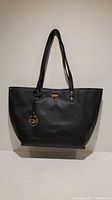 Front view of black BCBG Paris purse with gold logo charm showing overall shape and design