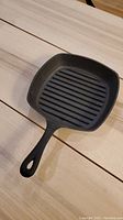 Top view of square cast iron grill pan showing grill ridges and handle.