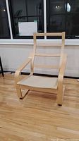 Front view of Ikea Poang chair showing curved wooden frame and beige fabric seat
