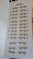 27 silver kitchen cupboard handles laid out in rows with most screws included; some screws missing.