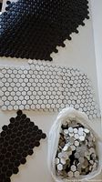 Black and white penny hex tiles shown together with bag of loose tiles, individual tiles about 1 inch in size.