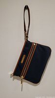 Photo of navy clutch with brown leather-like trim, gold zipper, and wrist strap