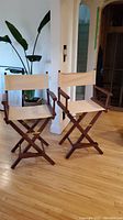 Pair of chairs front view showing wooden frames and beige canvas seating