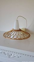 Side view of vintage pendant light showing rattan woven shade and white milk glass shade with attached wire and ceiling fixture.