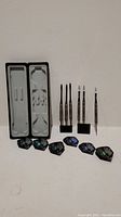 Full set of six darts with black shafts and wolf face flights alongside molded plastic carrying case