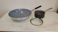 Photo of Paderno wok and GreenPan pot with lid on white surface.
