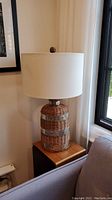 Image of the entire lamp showing the wicker and tin base, fabric shade, and overall size and shape